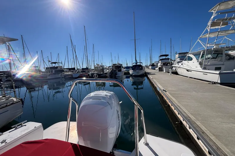 2022 Axopar 28 AFT CABIN docked at a sunny marina with sailboats.