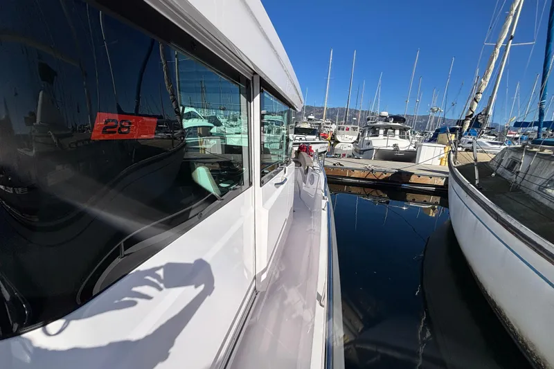 2022 Axopar 28 AFT CABIN docked at marina, reflecting clear blue sky.