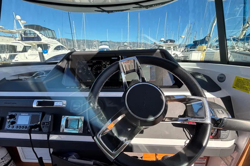 Interior view of 2022 Axopar 28 AFT CABIN boat cockpit with steering wheel and navigation controls.