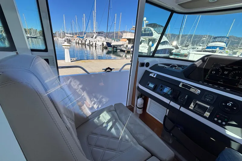 Interior view of 2022 Axopar 28 AFT CABIN, showcasing helm and marina backdrop.