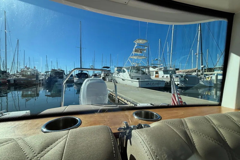 View from 2022 Axopar 28 AFT CABIN, overlooking marina with boats and clear blue sky.