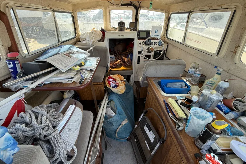 Interior of a cluttered 1996 C-Dory 22 boat with various items and equipment.