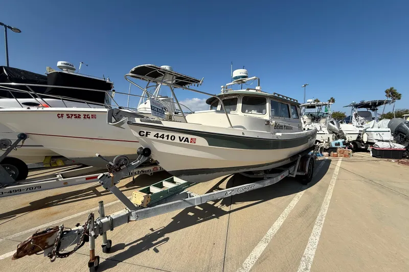 1996 C-Dory 22 boat on trailer in marina parking lot under clear blue sky.