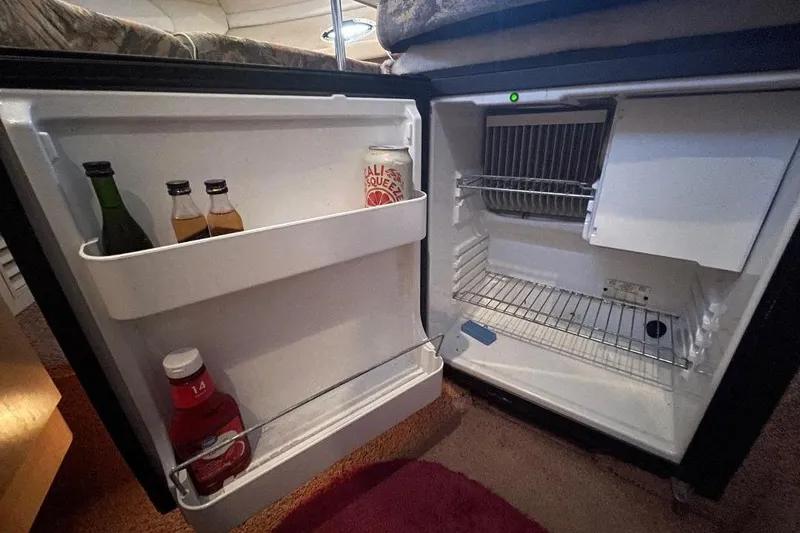 Mini fridge inside 2000 Bayliner 2655 Ciera Sunbridge, stocked with drinks and condiments.