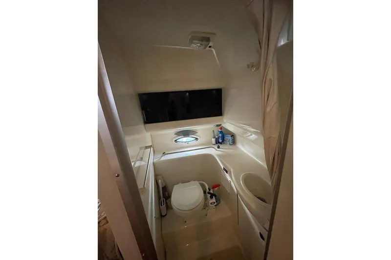 Compact bathroom in 2000 Bayliner 2655 Ciera Sunbridge boat, featuring toilet and sink.
