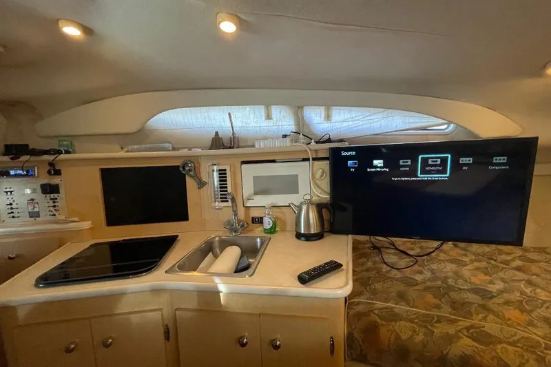 Interior of 2000 Bayliner 2655 Ciera Sunbridge with kitchenette and TV setup.