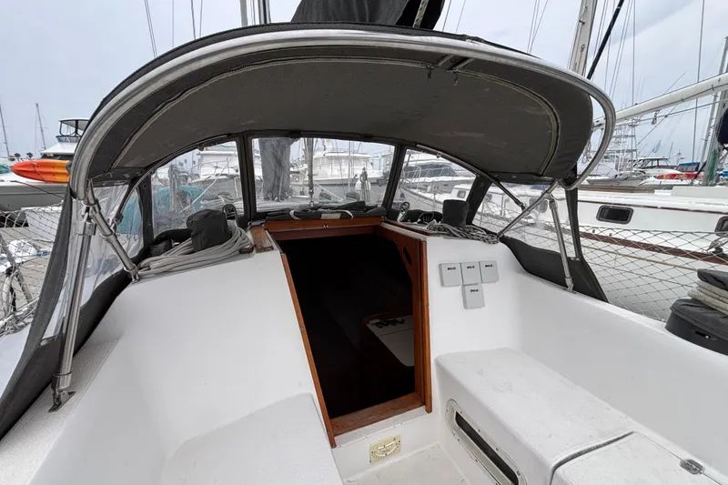 Cockpit of 1979 Islander Peterson 40 sailboat, featuring covered seating and marina view.