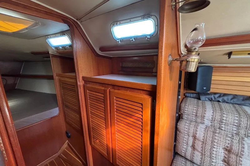 Interior of 1979 Islander Peterson 40 sailboat with wooden cabinets and vintage lamp.