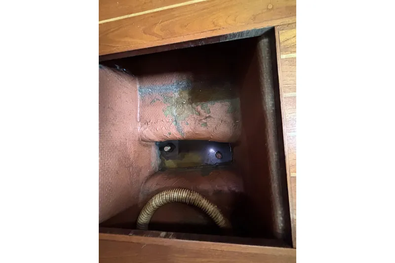 Bilge compartment of 1979 Islander Peterson 40 sailboat with visible hose and wood flooring.