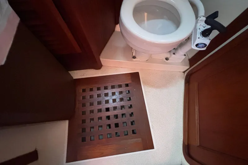 1979 Islander Peterson 40 yacht bathroom with wooden floor grate and marine toilet.