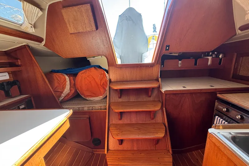 Interior of 1979 Islander Peterson 40 sailboat with wooden cabinetry and compact kitchen area.