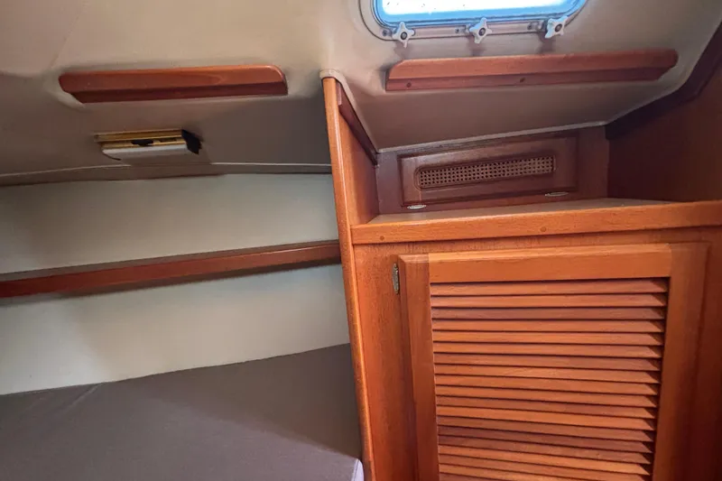 Interior of 1979 Islander Peterson 40 sailboat with wooden cabinetry and small window.