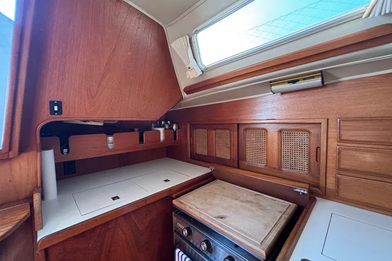Interior of 1979 Islander Peterson 40 sailboat, featuring a wooden galley with stove and storage.