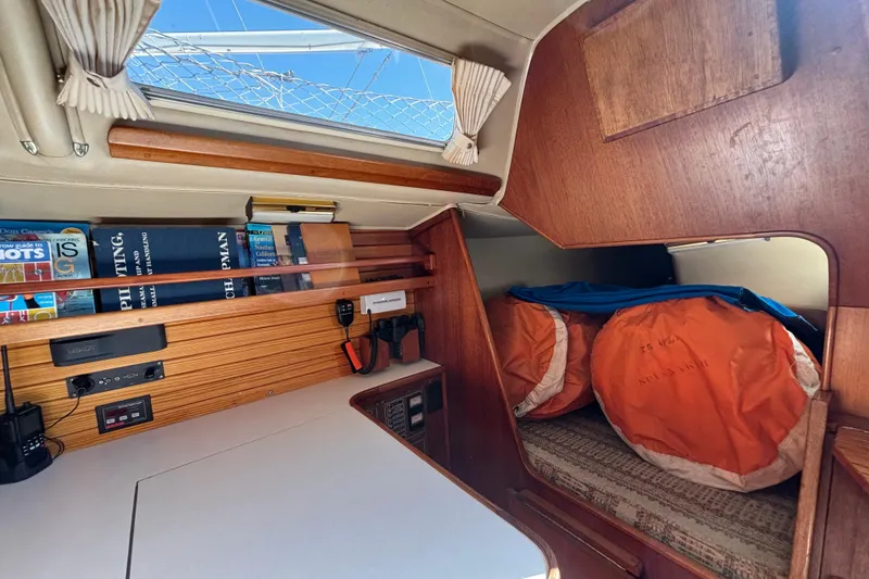 Interior of 1979 Islander Peterson 40 sailboat with books, electronics, and storage area.