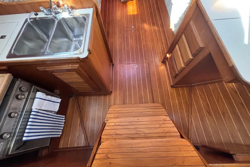 Wooden interior of 1979 Islander Peterson 40 sailboat with sink and stove.