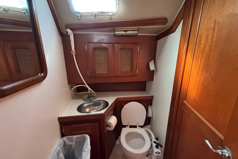 1979 Islander Peterson 40 yacht bathroom with wooden cabinets, sink, and toilet.