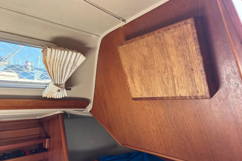 Interior of 1979 Islander Peterson 40 sailboat with wooden paneling and window curtain.