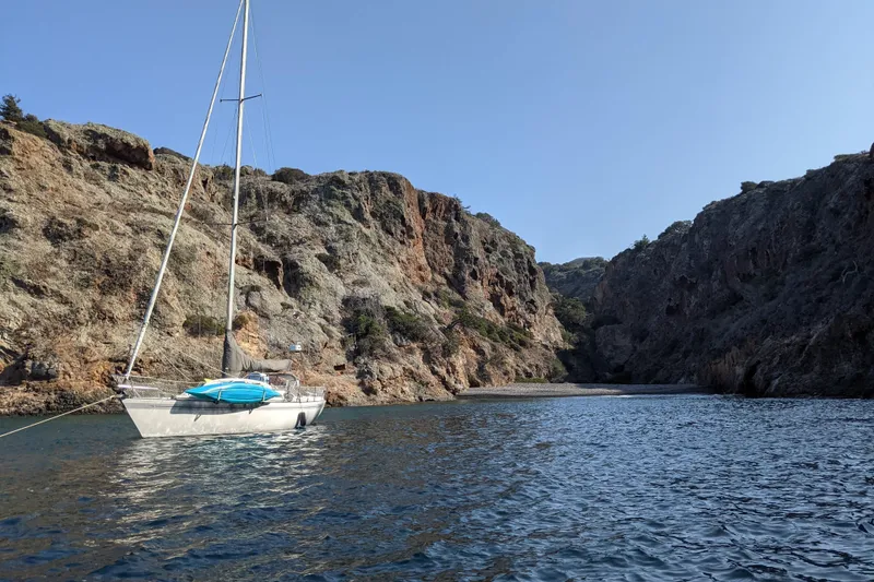 Sailboat Islander Peterson 40 (1979) anchored in a scenic rocky cove.