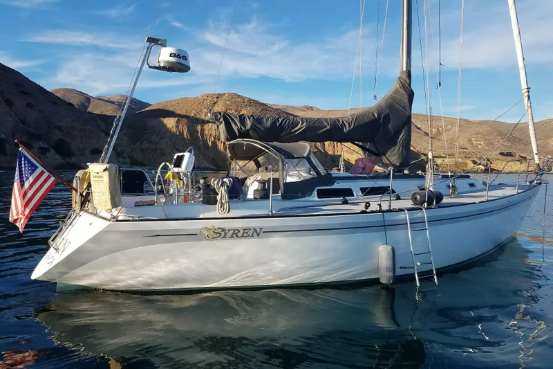 1979 Islander Peterson 40 sailboat anchored in scenic coastal waters with American flag.