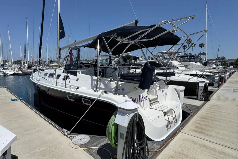2004 Hunter 41 Aft Cockpit sailboat docked at marina under clear blue sky.