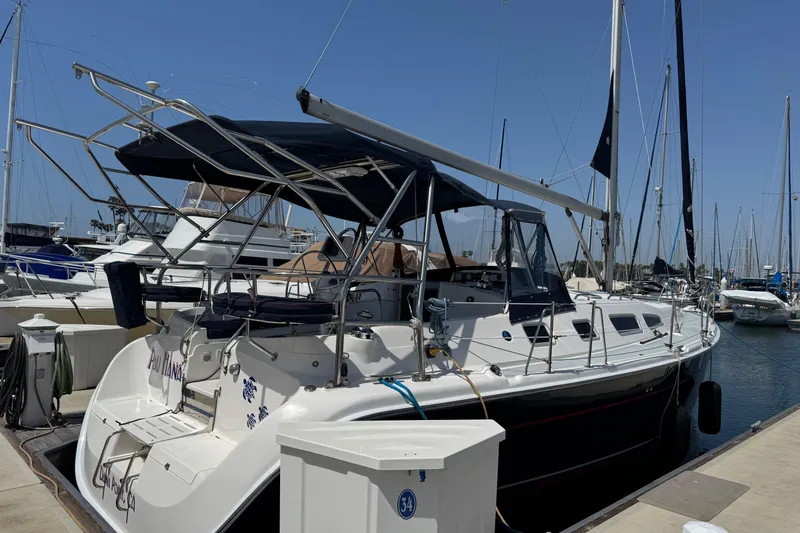 2004 Hunter 41 Aft Cockpit sailboat docked at marina under clear blue sky.