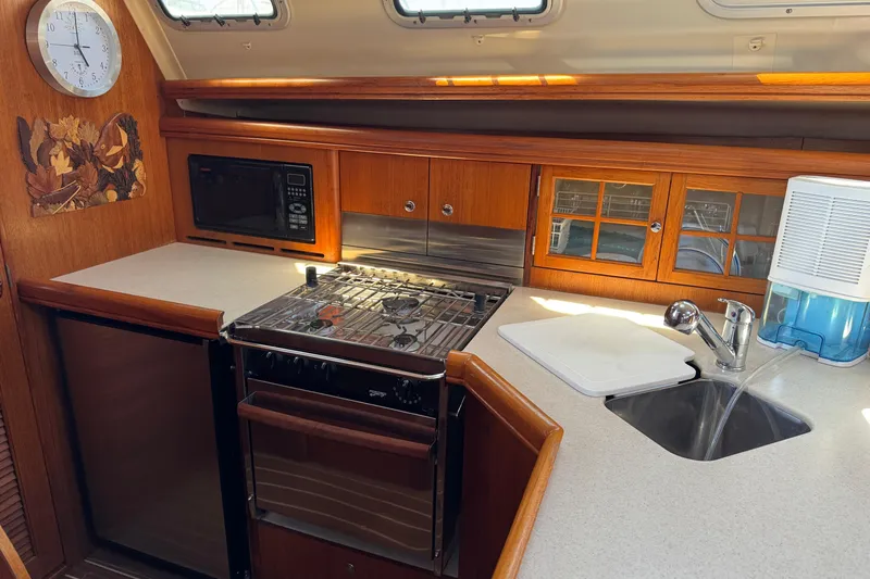Galley kitchen in 2004 Hunter 41 Aft Cockpit sailboat with stove, sink, and microwave.