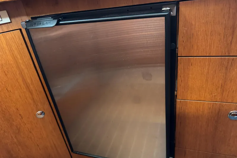 Wooden cabinetry with a stainless steel fridge on a 2004 Hunter 41 Aft Cockpit yacht.