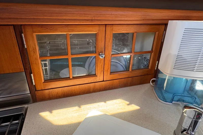 Wooden cabinet with glass doors in 2004 Hunter 41 Aft Cockpit yacht kitchen.