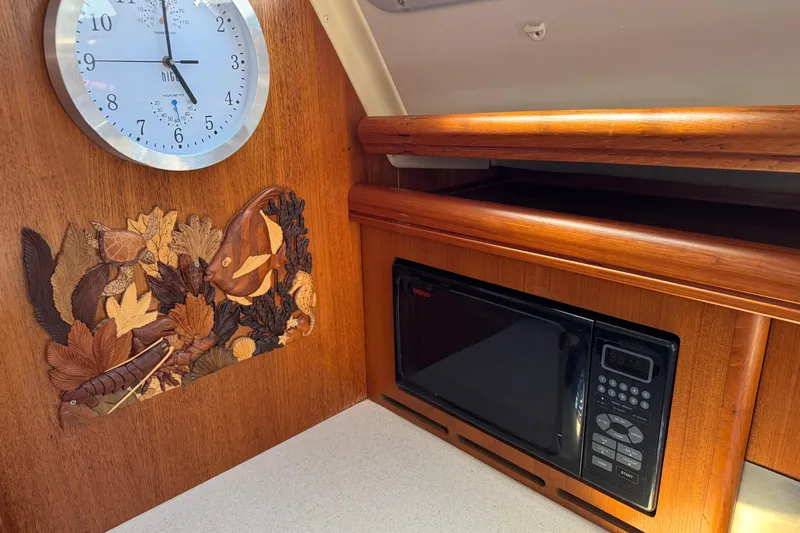Wooden interior of 2004 Hunter 41 Aft Cockpit with clock, microwave, and decorative panel.