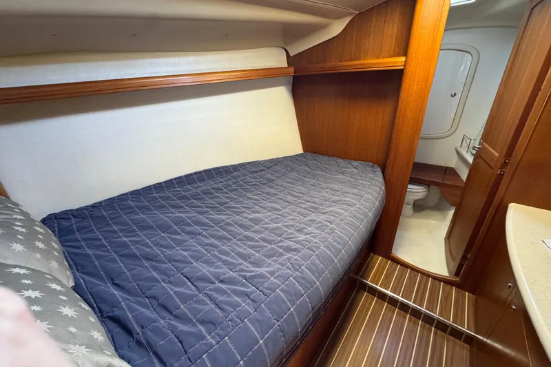 Cozy cabin interior of 2004 Hunter 41 Aft Cockpit sailboat with wooden finish and bed.