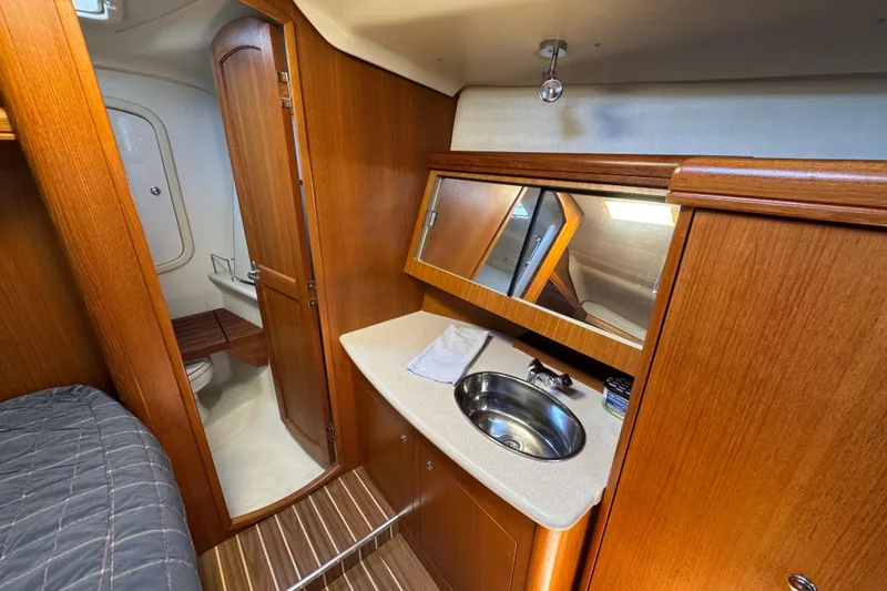 Interior of 2004 Hunter 41 Aft Cockpit yacht with wooden cabinetry and compact bathroom.