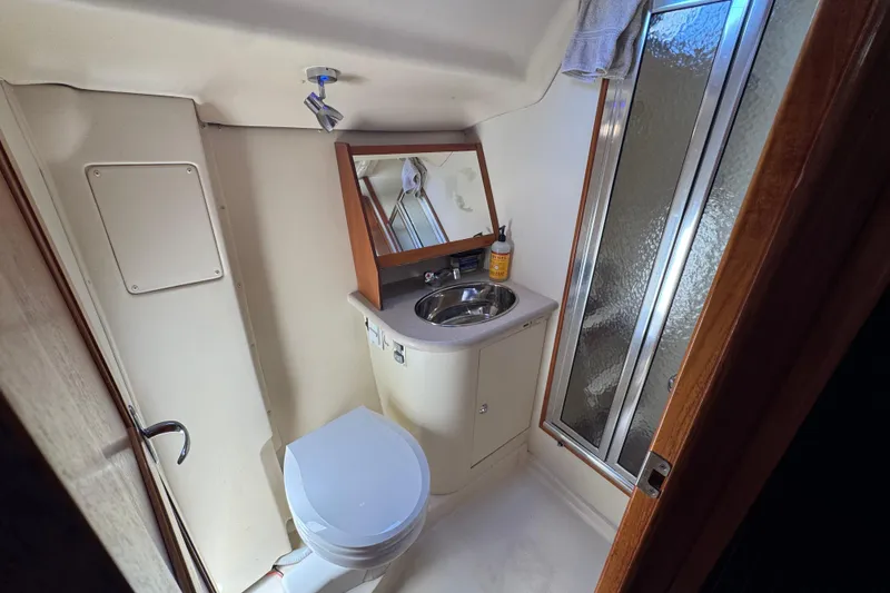 Compact bathroom in 2004 Hunter 41 Aft Cockpit yacht with sink, toilet, and shower.