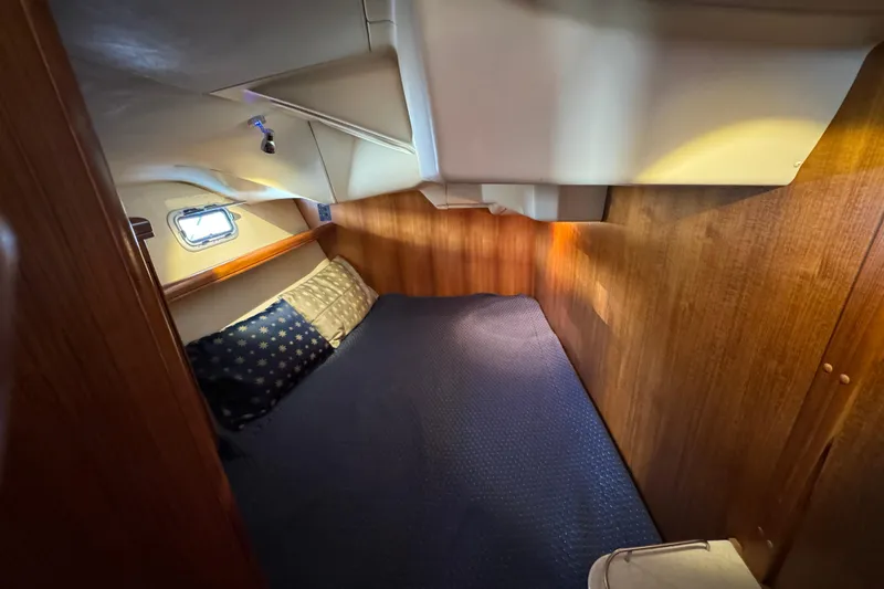 Cozy cabin interior of 2004 Hunter 41 Aft Cockpit sailboat with wooden paneling and bedding.
