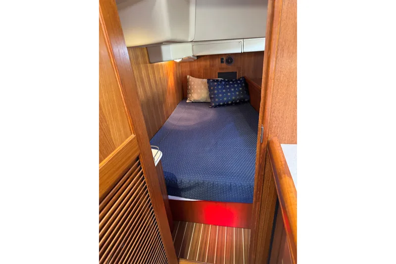 Cozy cabin interior of 2004 Hunter 41 Aft Cockpit sailboat with wooden paneling and bedding.