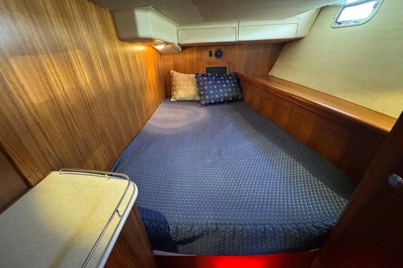 Cozy cabin interior of 2004 Hunter 41 Aft Cockpit sailboat with wood paneling and bedding.