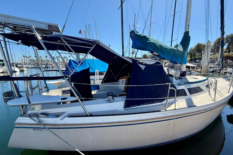 1988 Catalina 34 sailboat docked in marina, featuring blue canvas covers and sleek design.
