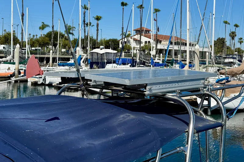 Catalina 34 sailboat with solar panel, docked in a marina, surrounded by palm trees.