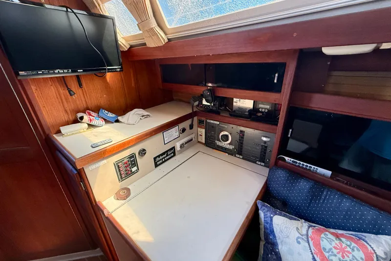 Navigation station inside a 1988 Catalina 34 sailboat with control panels and a mounted TV.