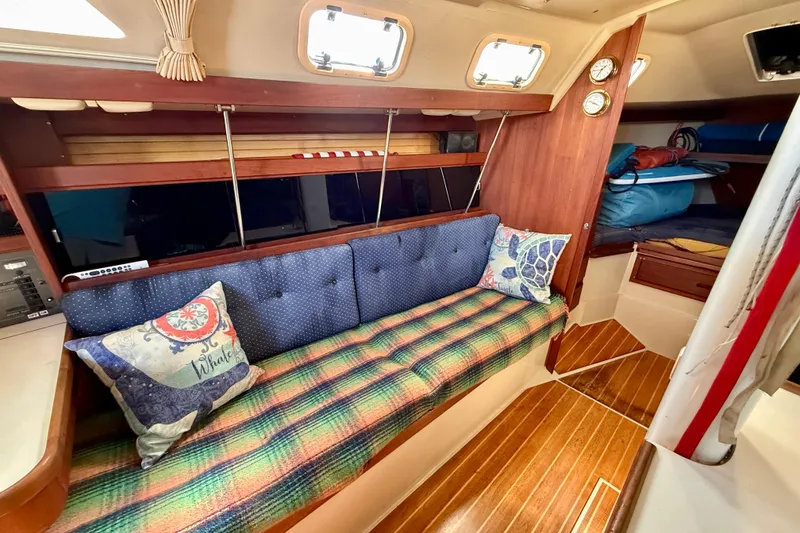 Interior of a 1988 Catalina 34 sailboat with cozy seating and nautical decor.