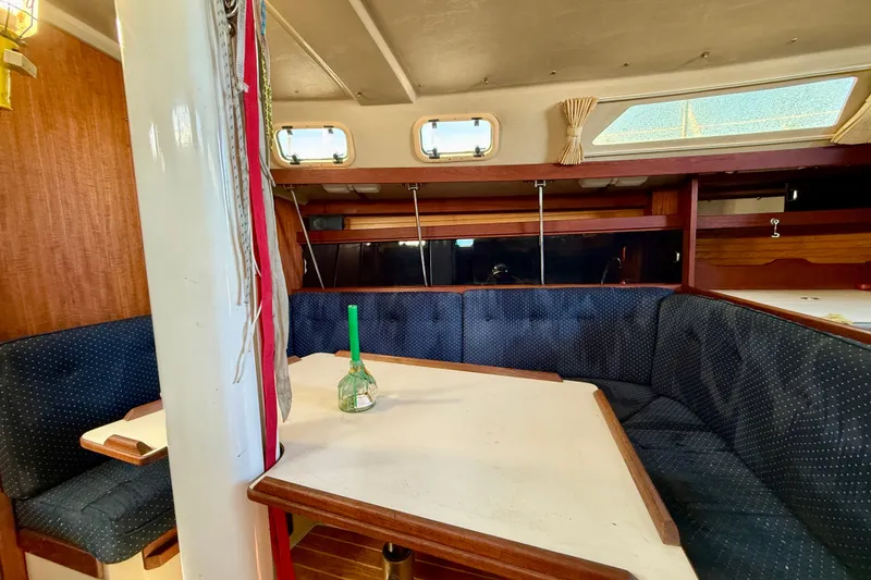 Interior of a 1988 Catalina 34 sailboat with a cozy dining area and blue upholstery.
