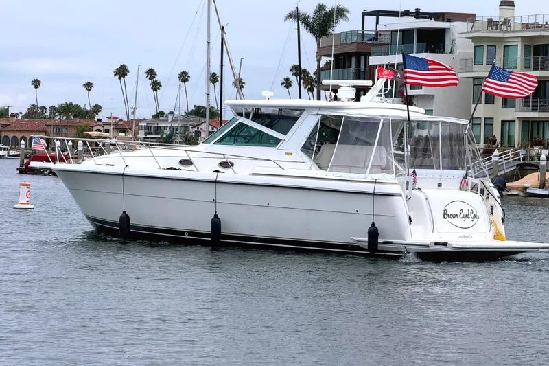 2004 Tiara Yachts 4000 Express cruising in a marina with American flags displayed.