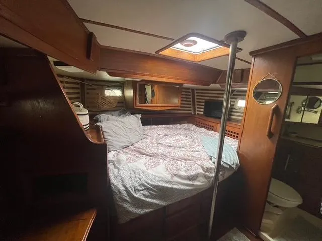 Cozy cabin interior of 1981 Endeavour 43 Center Cockpit Ketch with wooden furnishings and bed.