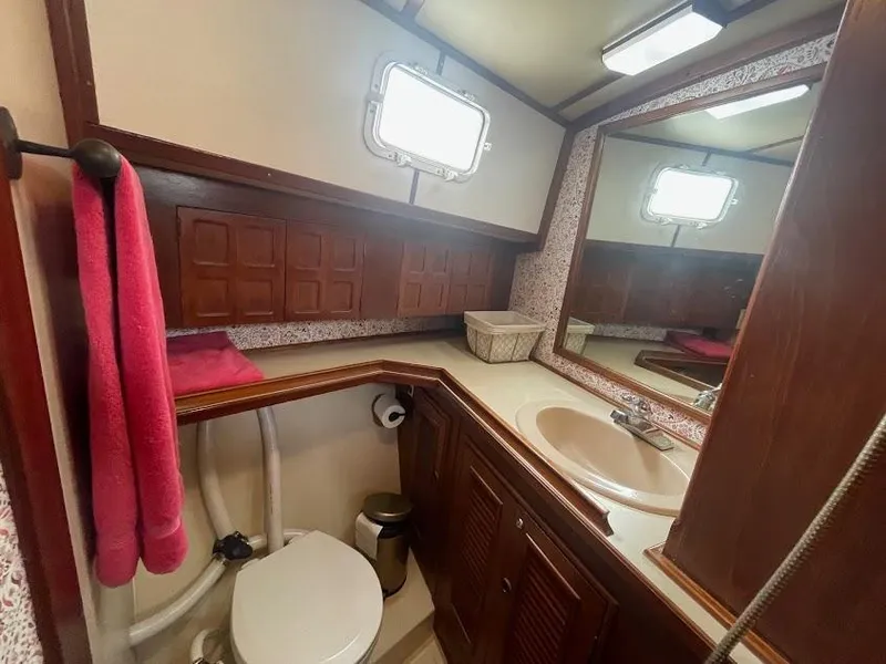 Bathroom interior of 1981 Endeavour 43 Center Cockpit Ketch, featuring sink, toilet, and mirror.