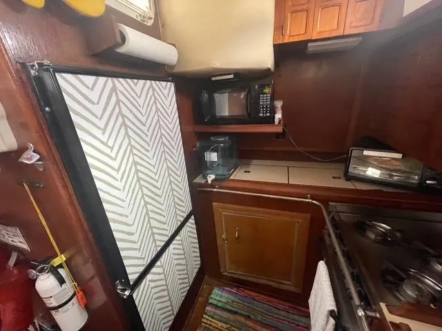 Compact kitchen in 1981 Endeavour 43 Center Cockpit Ketch with appliances and wood cabinetry.