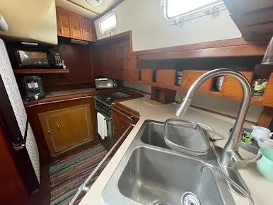 1981 Endeavour 43 Center Cockpit Ketch galley with wooden cabinetry and stainless steel sink.