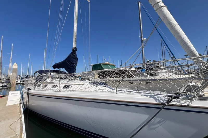 Sailboat docked at marina, Catalina 42 model, 1990, under clear blue sky.