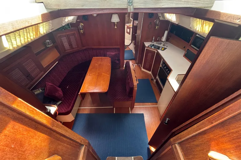 Interior of a 1990 Catalina 42 sailboat with wood finish and cozy seating area.