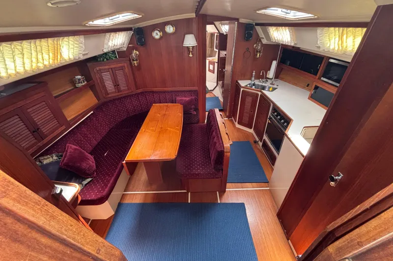Interior of a 1990 Catalina 42 sailboat with wood finishes and cozy seating area.
