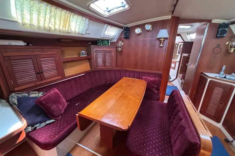 Interior of a 1990 Catalina 42 sailboat with cozy dining area and wooden furnishings.
