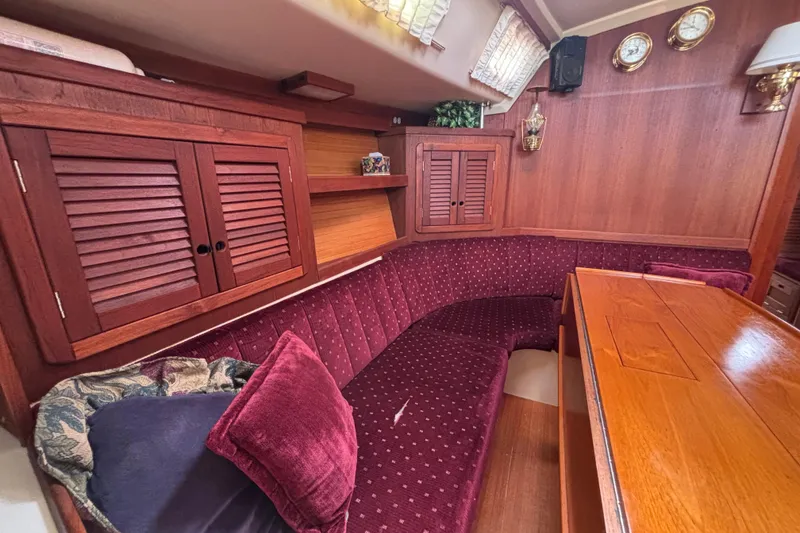 Interior of a 1990 Catalina 42 sailboat with plush seating and wooden cabinetry.